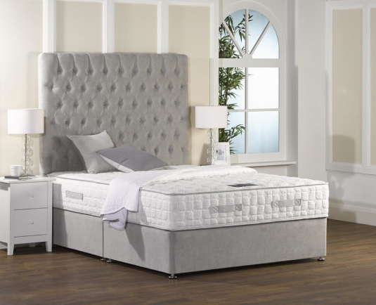 Grey divan bed with matching mattress in a modern, styled bedroom.